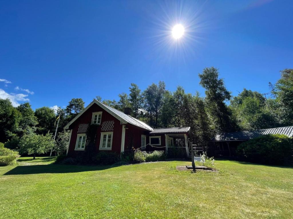 a red house on a lawn with the sun in the sky at Haus Paula in Sjötorp