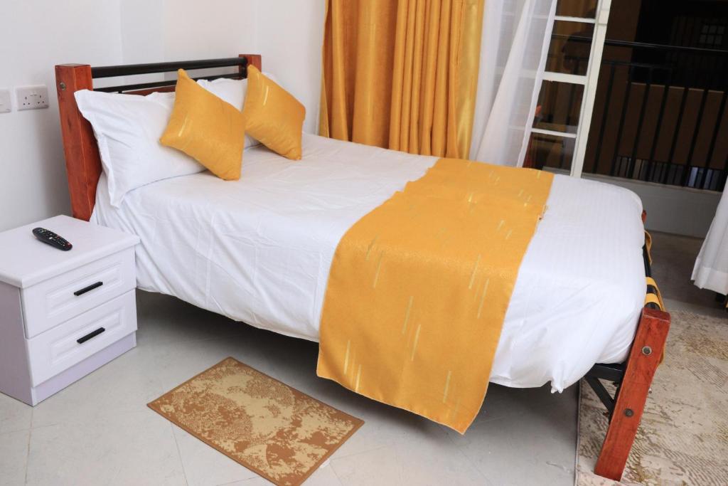 a bedroom with a bed with an orange blanket on it at Kwetu properties in Nairobi