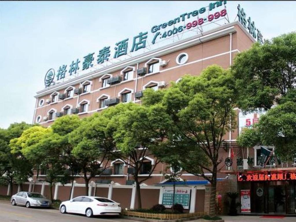 a pink building with cars parked in front of it at GreenTree Inn ShangHai KangQiao Industrial Zone JinXiu Road Business Hotel in Shanghai