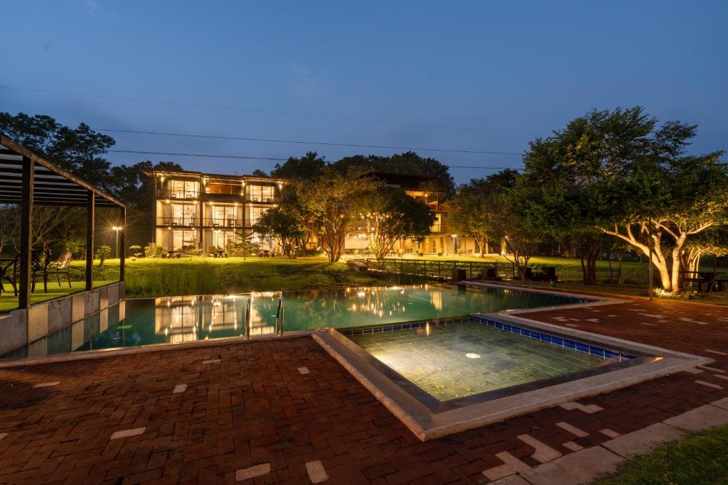 a swimming pool at night with a house in the background at Trio Lodge- Habarana in Habarana