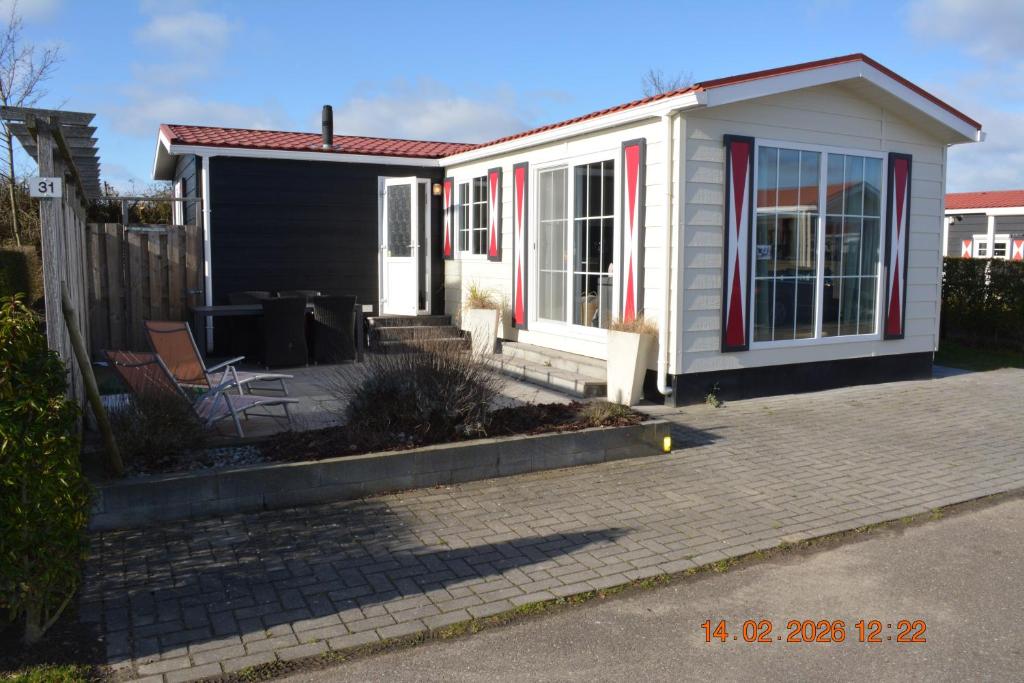 a small white house with a patio in front of it at ZEEMEEUW - Platz 31, Olmenduin in Serooskerke