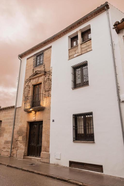 a white building with black windows on a street at Boutique Casa de los Pedraza in Baeza