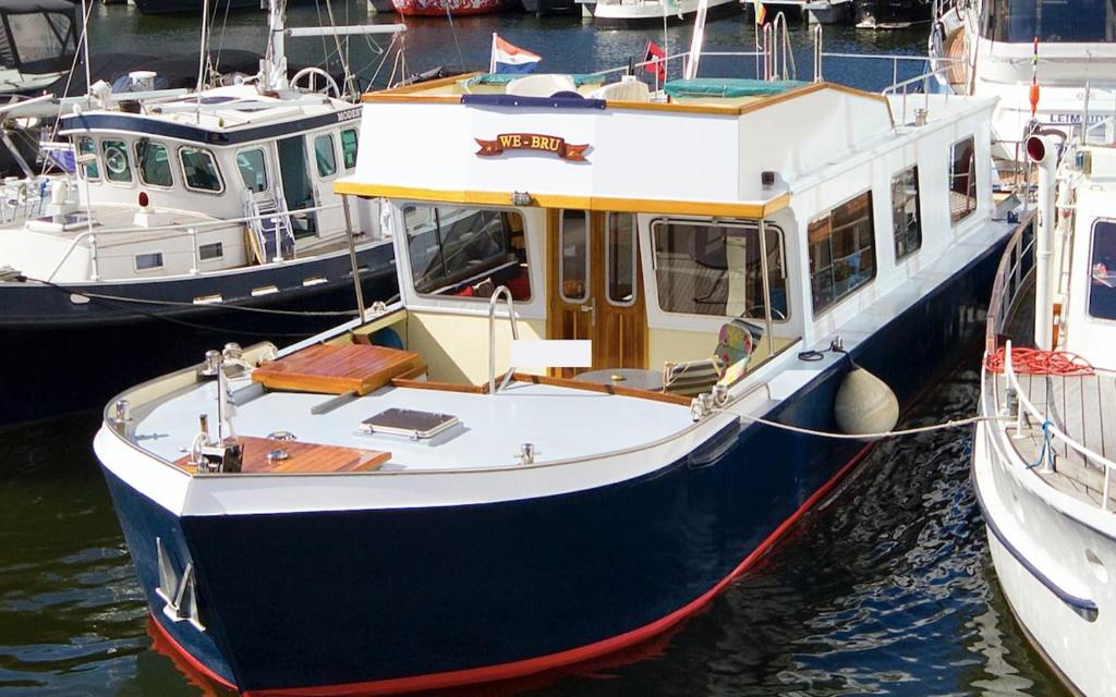 a blue and white boat is docked in the water at Authentic houseboat Amalia in Amsterdam