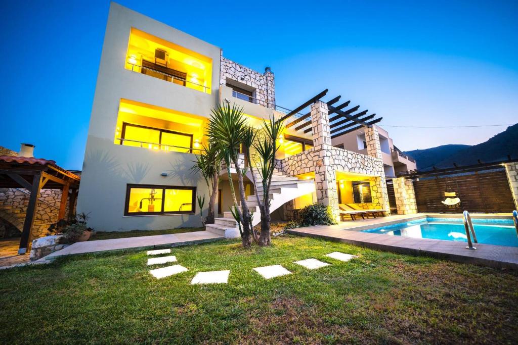 a house with a swimming pool in front of it at Villa Majestic Heated Pool Sauna & Endless Sea Views in Megála Khoráfia