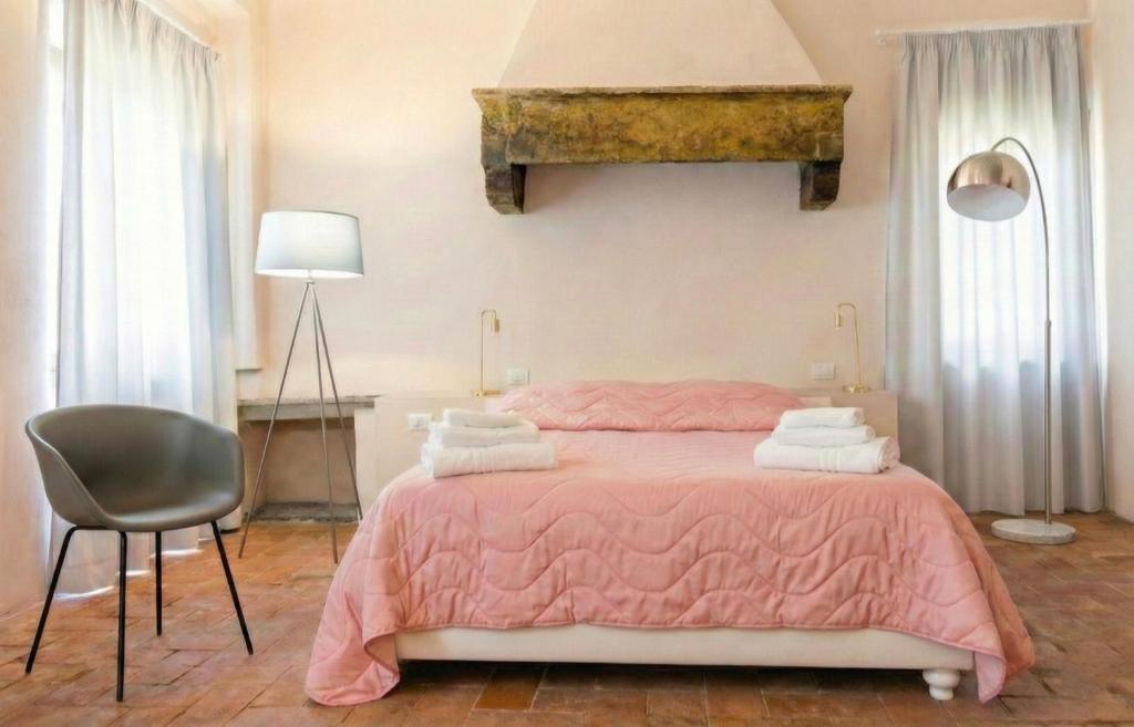 a bedroom with a pink bed and a chair at Allegra Toscana - Affittacamere Guest house Arezzo in Arezzo