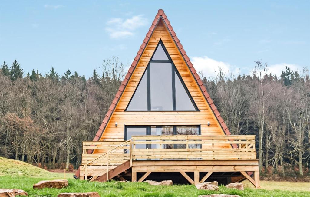 a cabin with a triangular roof on top of a field at Confortable Chalet Moderne in Anould