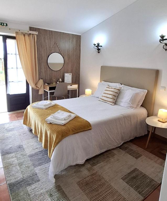 a bedroom with a large white bed and a table at Quinta das AVES - Double Bedroom 1 in Odiáxere