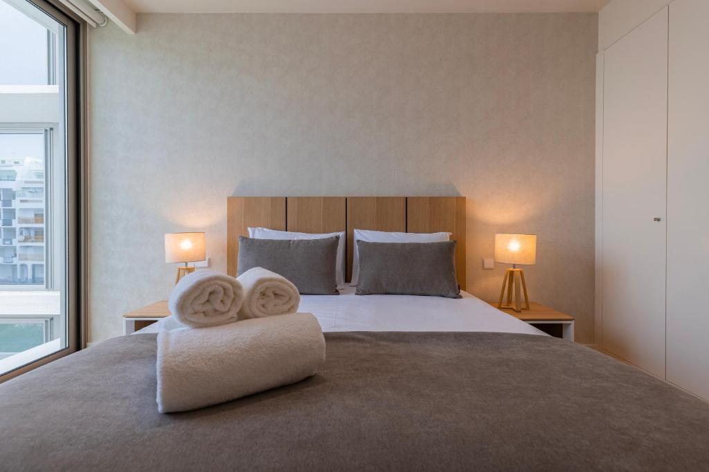 a bedroom with a large bed with two towels on it at Bayline - Bezugo by Bedzy in Armação de Pêra