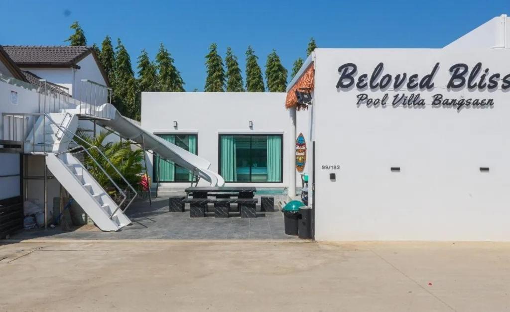 a white building with a slide next to a park with benches at Beloved Bliss Pool Villa Bangsaen พูลวิลล่าบางแสนมีสไลด์เดอร์ in Chon Buri