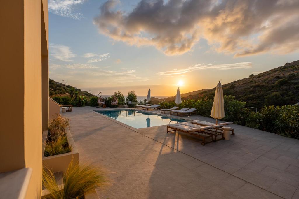 a villa with a swimming pool and a sunset at Oleander Evia in Agioi Apostoli