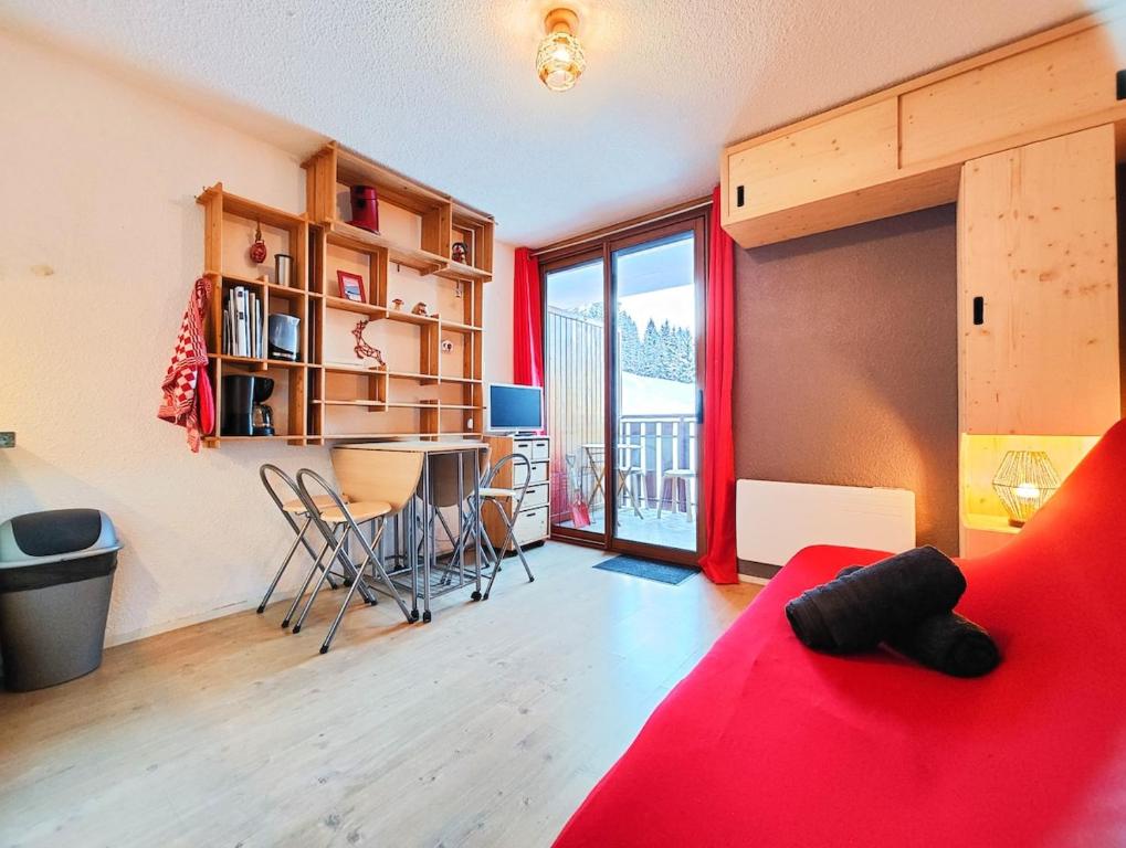 a living room with a red couch and a table at Charmant studio montagne - vue dégagée - pied des pistes in Mijoux