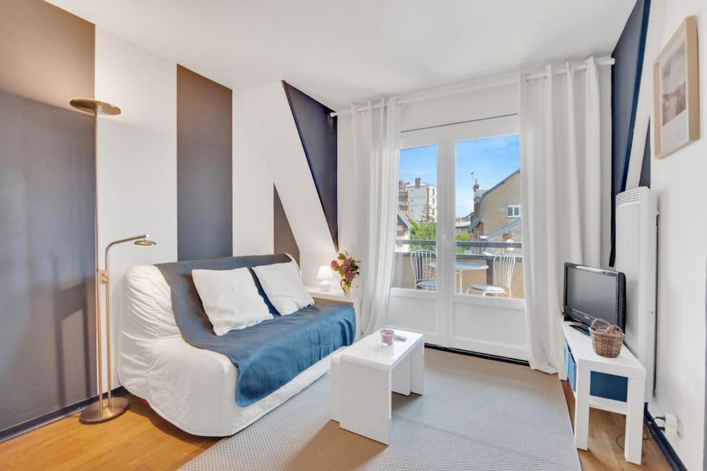 a bedroom with a bed and a tv and a window at L'Échappée Belle de Houlgate 2 personnes in Houlgate