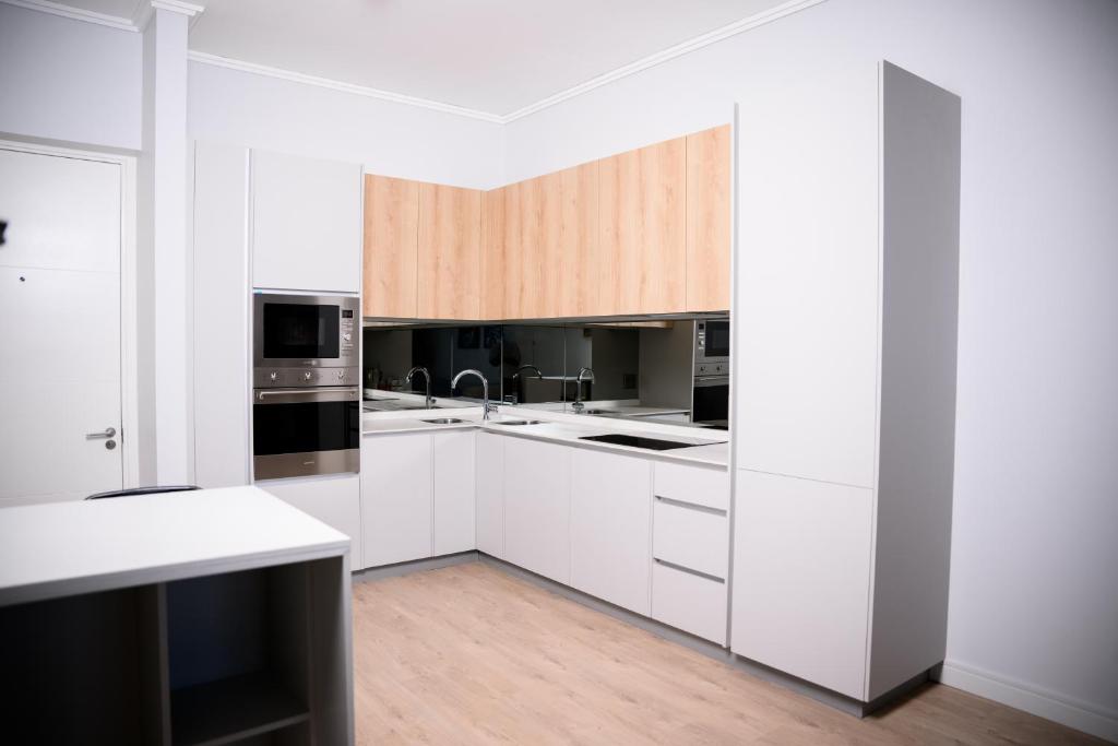 a kitchen with white cabinets and black appliances at SoftStay Ellipse Luxury Apartment in Midrand