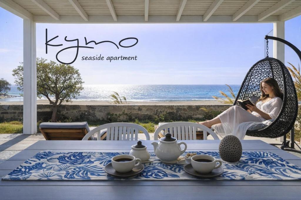a woman sitting in a swing reading a book at KYMO Private Seafront Residence in Koutsourás