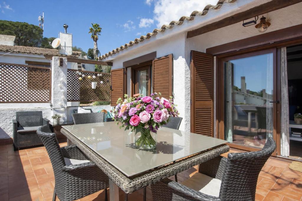 a table with a vase of flowers on a patio at Casa Tossa – Piscina, Vistas Mar y A/C (6 pax) in Tossa de Mar