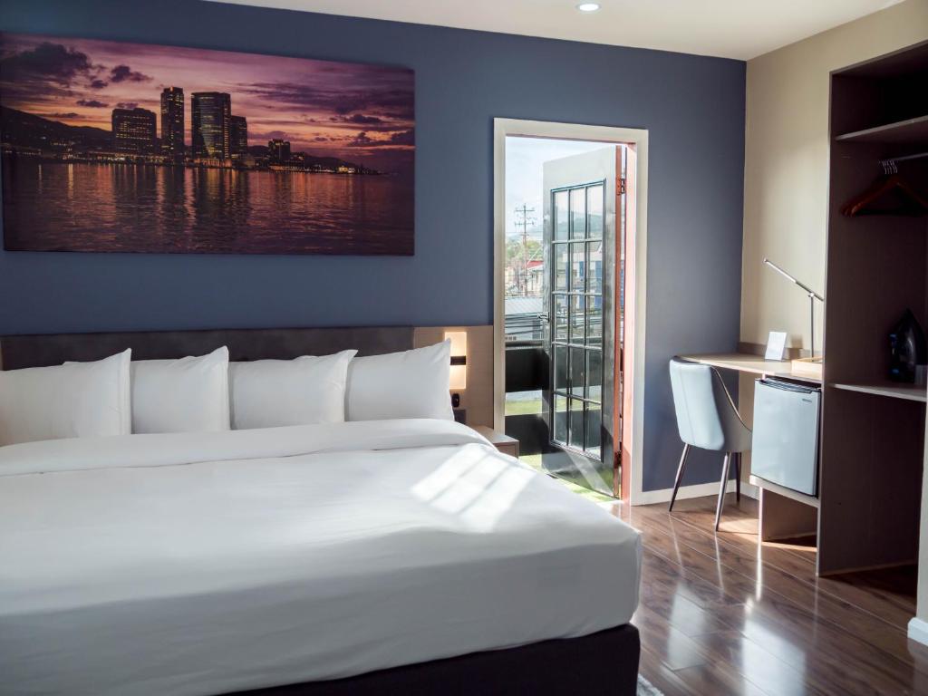 a bedroom with a large white bed and a desk at TStays Smart Hotel Courtyard, Gated Modern Stay in Port-of-Spain