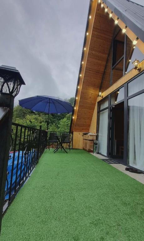 a house with a patio with an umbrella and a pool at Mountain Hearth in Zeda Ch'khutunet'i