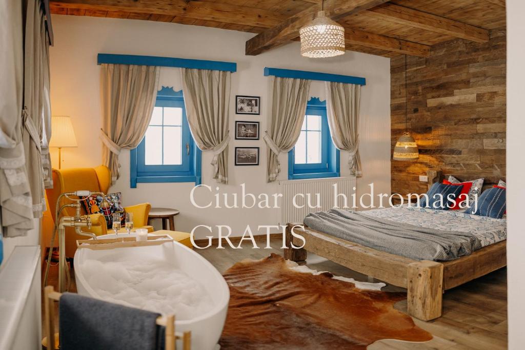 a bedroom with blue windows and a bed with a tub at Heritage Guesthouse in Bartoştana