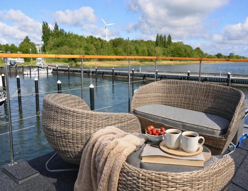 two wicker chairs and a table with a bowl of fruit at ÖKO Budget Hausboot Retreat Morgenrot in Stralsund