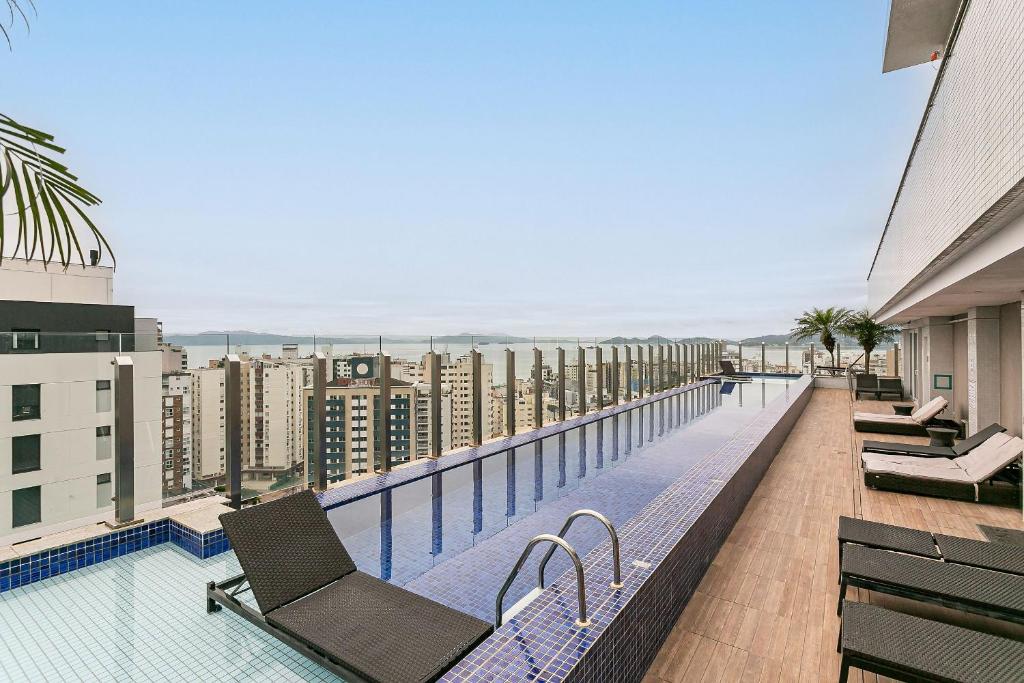 a balcony with chairs and a swimming pool on a building at WI-FI 200MB | Rooftop | Pool with Sea View #CA70D in Florianópolis