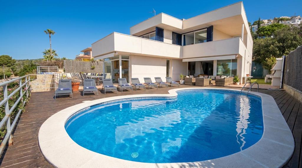 a villa with a swimming pool in front of a house at Villa Med A 2 kilometros andando de la playa, del puerto de Aguadoç y a 4 del centro de Sitges Muy Soleada todo el dia Capacidad superior a 16 personas NO REQUIERE COCHE in Sitges