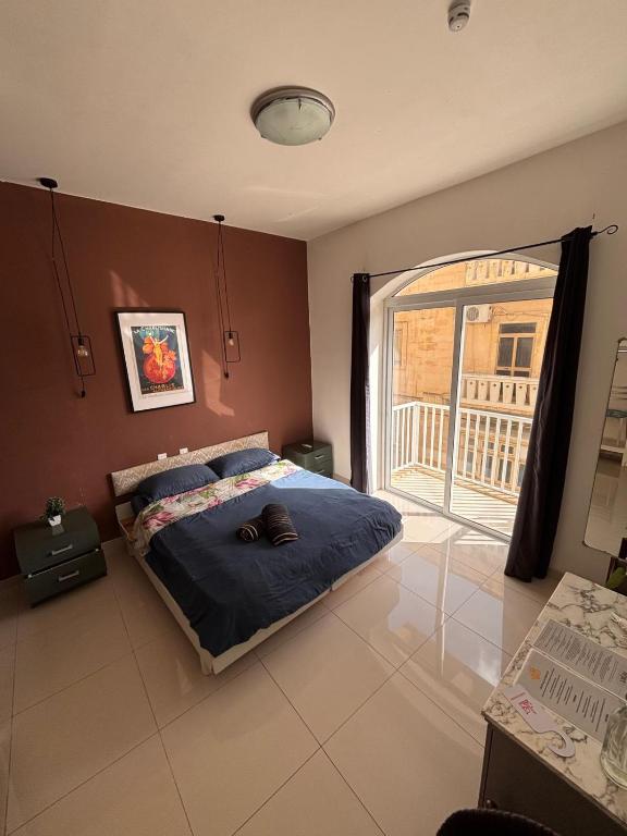 a bedroom with a bed and a large window at Sliema Central with Balcony Airconditioned and Comfortable Self Check IN in Il-Gżira