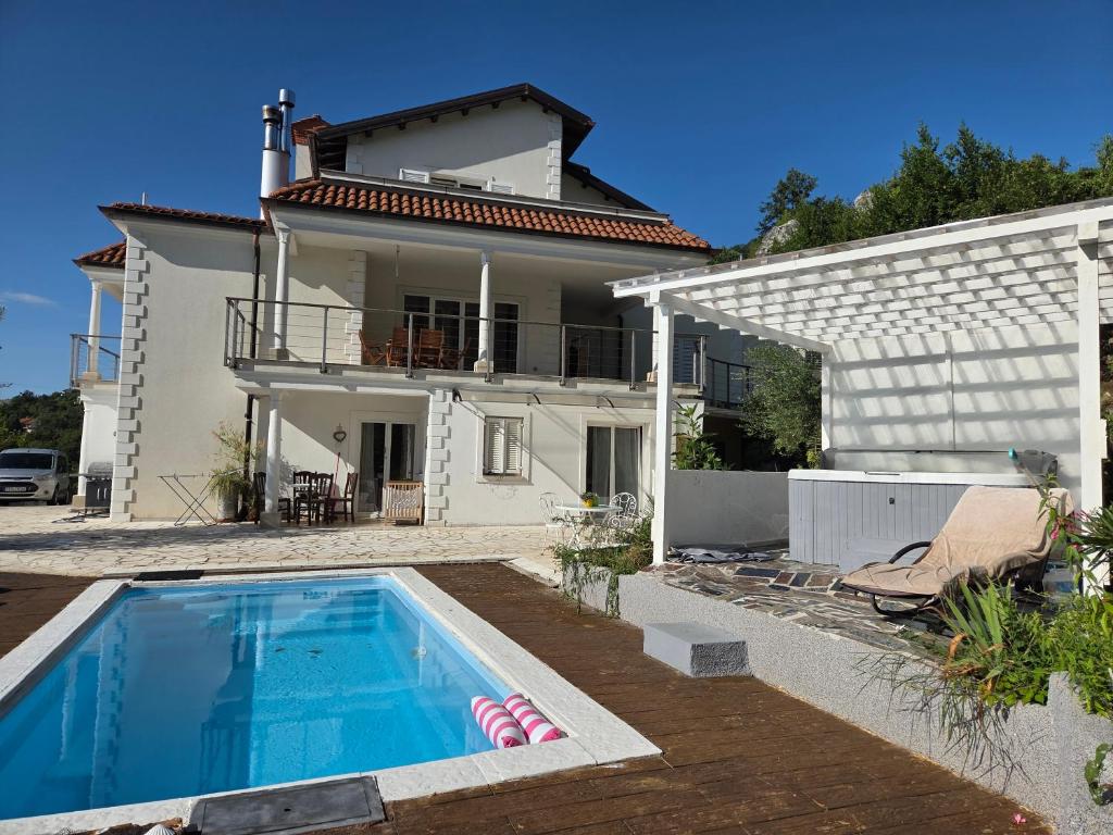 a villa with a swimming pool in front of a house at Apartment für 4 Personen mit Jacuzzi und Pool in Lovran