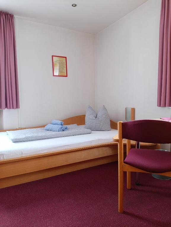 a bedroom with a bed and a chair in a room at Haus Lutherrose in Neuendettelsau