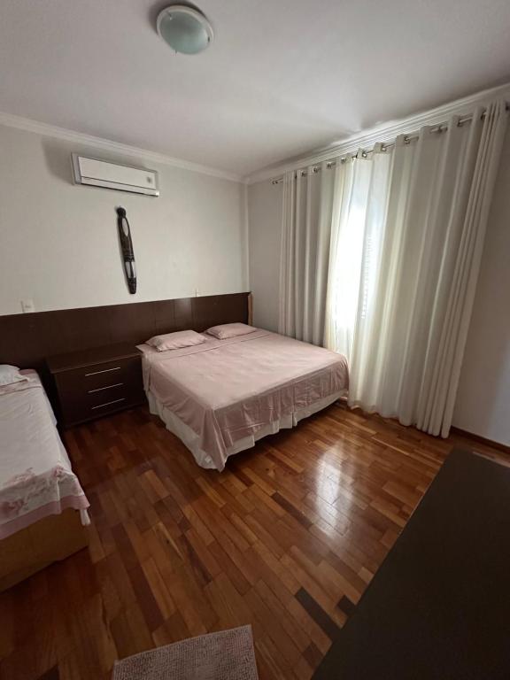 a small bedroom with two beds and a window at Hostel Muarama in Passos