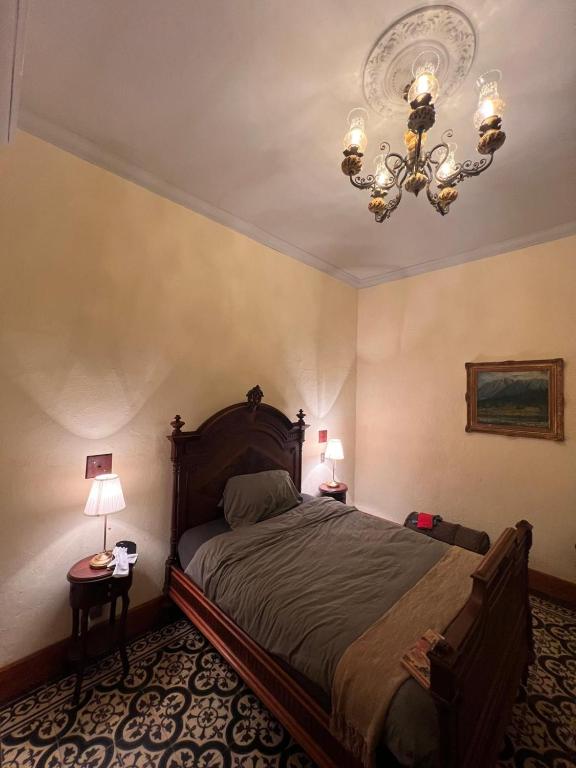 a bedroom with a bed and a chandelier at Posada La Pastora Colonial in Caracas