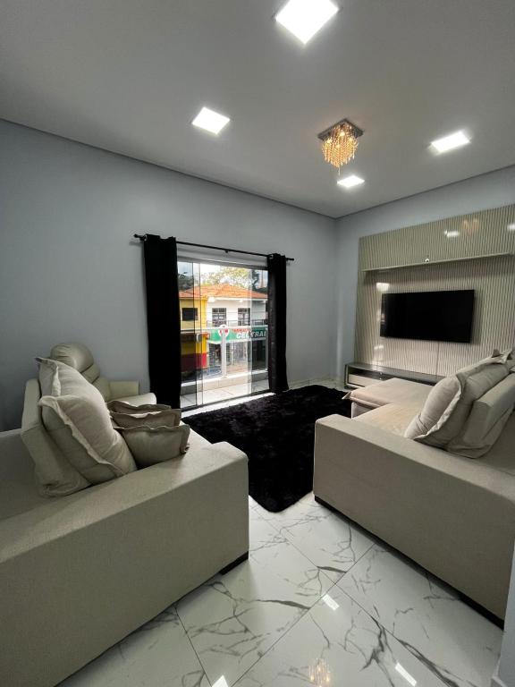 a living room with two couches and a flat screen tv at Apartamento no Centro de Sengés Quarto 01 in Sengés