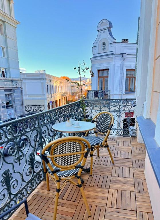a patio with two chairs and a table on a balcony at Arts Hotel by Square in Tbilisi City