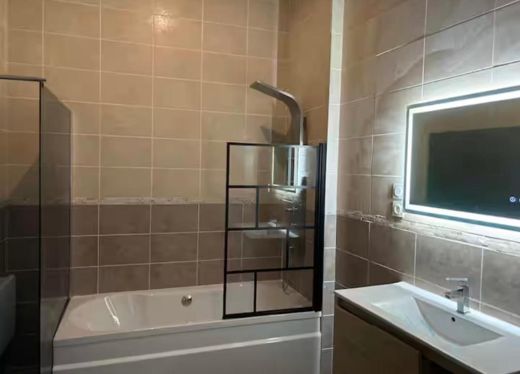 a bathroom with a tub and a sink and a mirror at Chez aurelie in Agnin