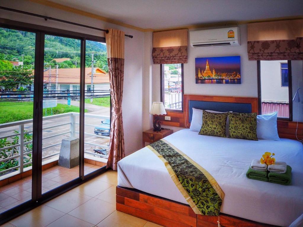 a bedroom with a large bed and a balcony at Lanta at Home - SHA Extra Plus in Ko Lanta