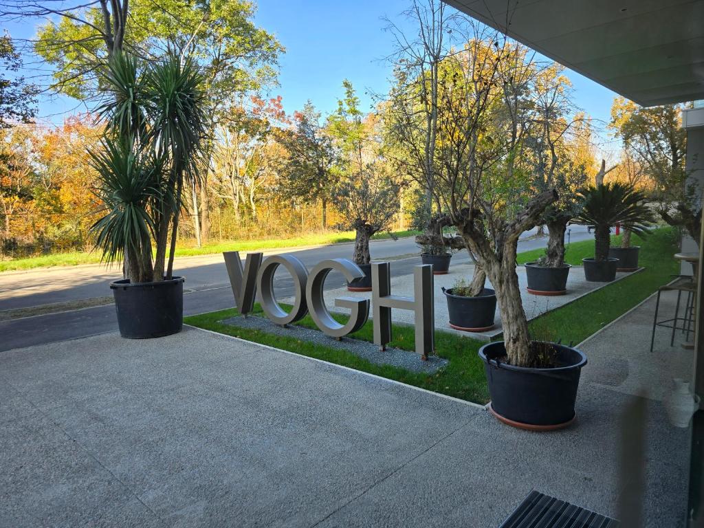 a sign with trees in pots next to a street at Apart HOTEL VOGH OLIMP - S605 in Văleni