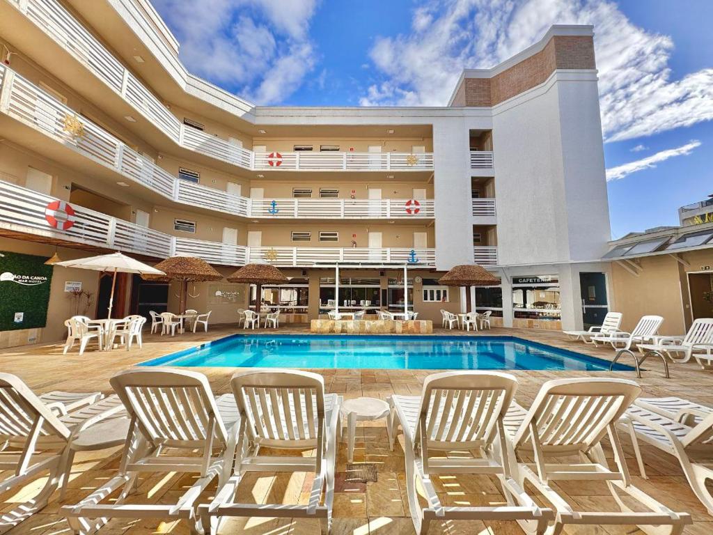 a pool at a hotel with chairs and tables at CAPÃO Da CANOA MAR HOTEL in Capão da Canoa