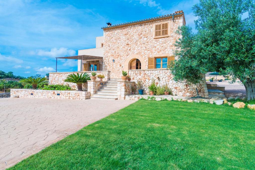 kamienny dom z zielonym trawnikiem przed nim w obiekcie Casa Puig De Na Franquesa w Manacorze