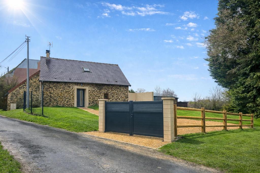 a stone house with a gate on the side of a road at Gite la pause corrézienne in Troche