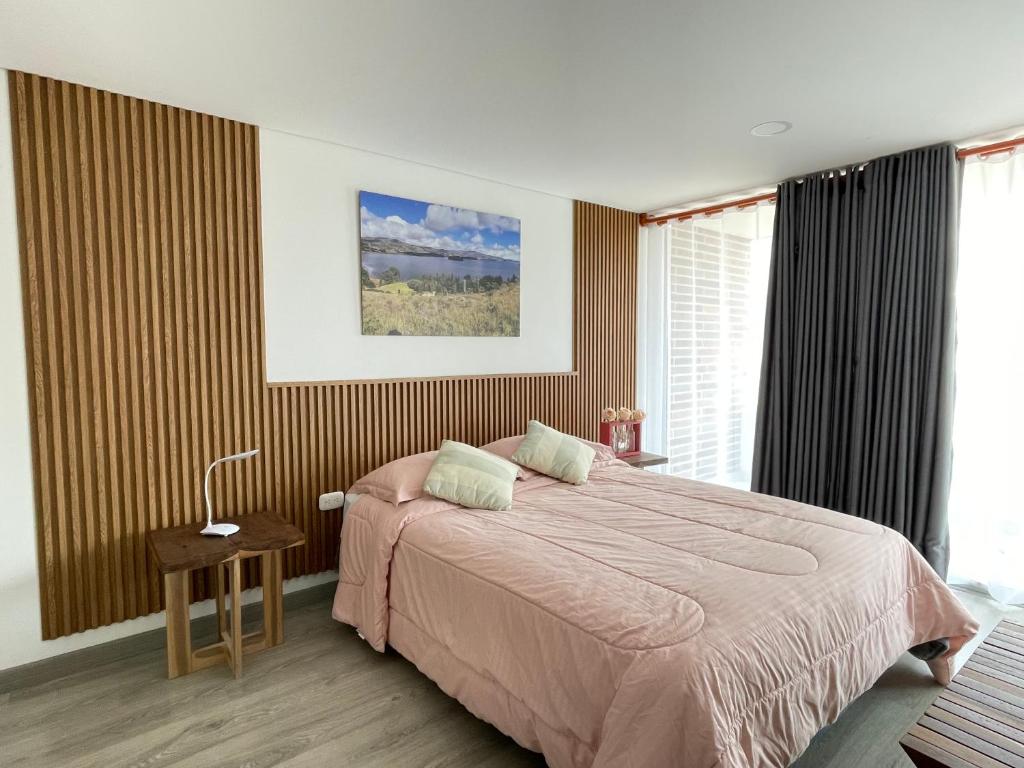 a bedroom with a bed with a pink blanket at Cómodo Apto Lago Sochagota in Paipa