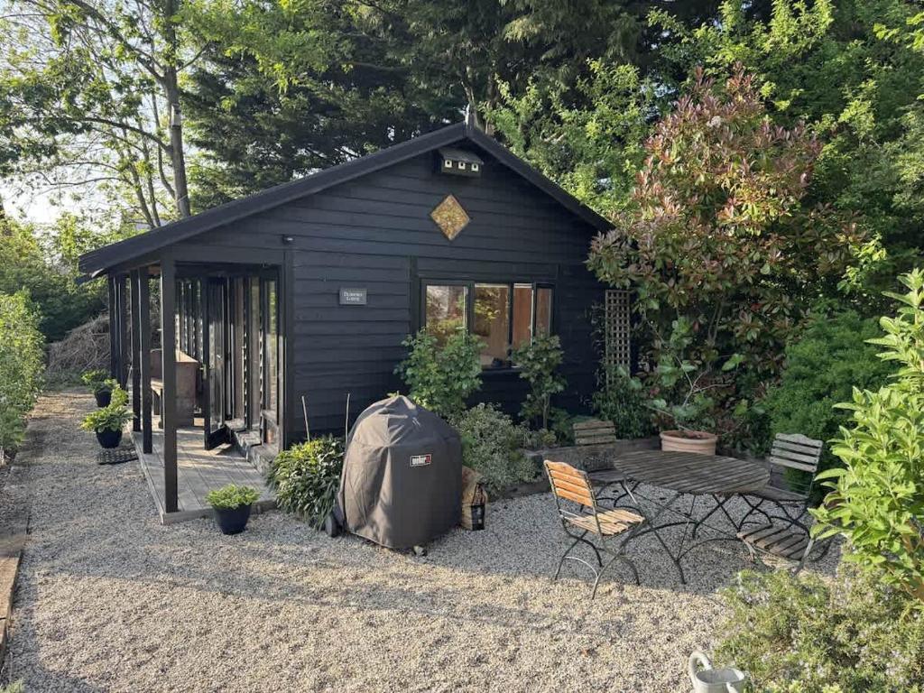 a black shed with a tent and chairs in front of it at Duxford Lodge, Cholsey in Cholsey