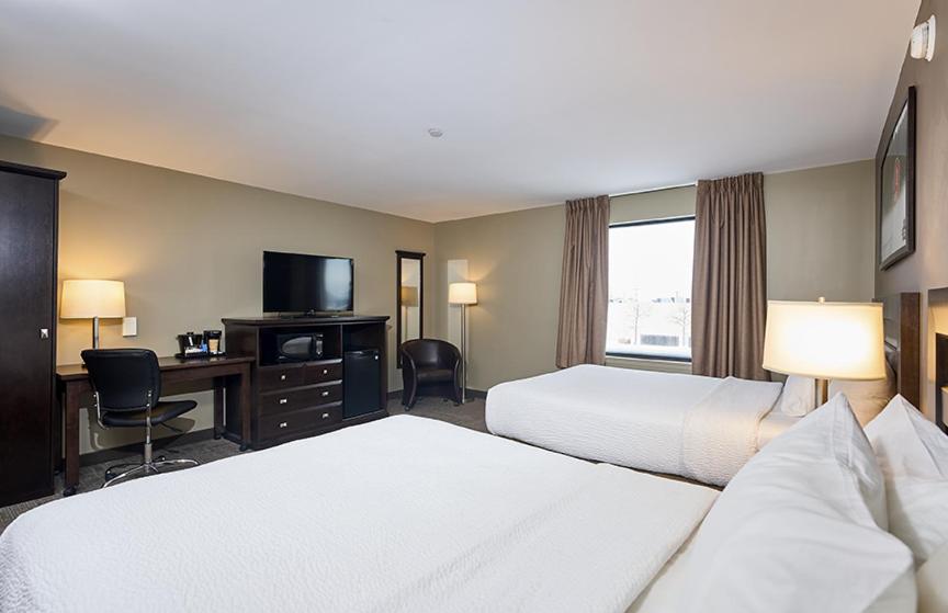 a hotel room with two beds and a desk and a television at Canad Inns Destination Centre Transcona in Winnipeg