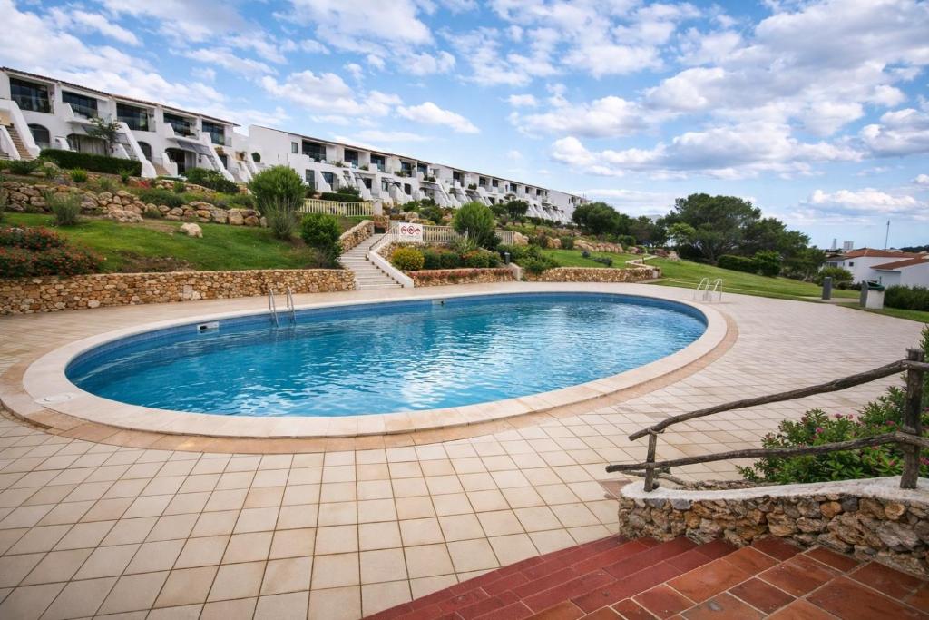 a swimming pool in front of a building at Costa Arenal - Biniplaya in Arenal d'en Castell