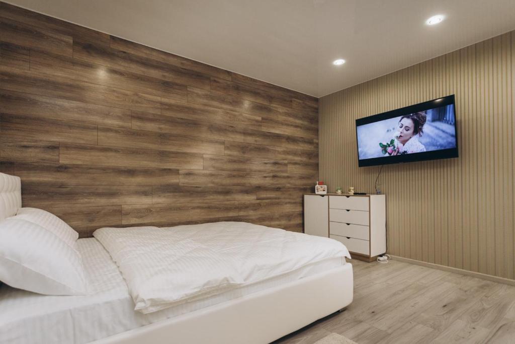 a bedroom with a white bed and a tv on a wall at Apart Center in Sumy
