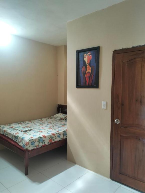 a small bedroom with a bed and a wooden door at PAULIN Surf in Montañita