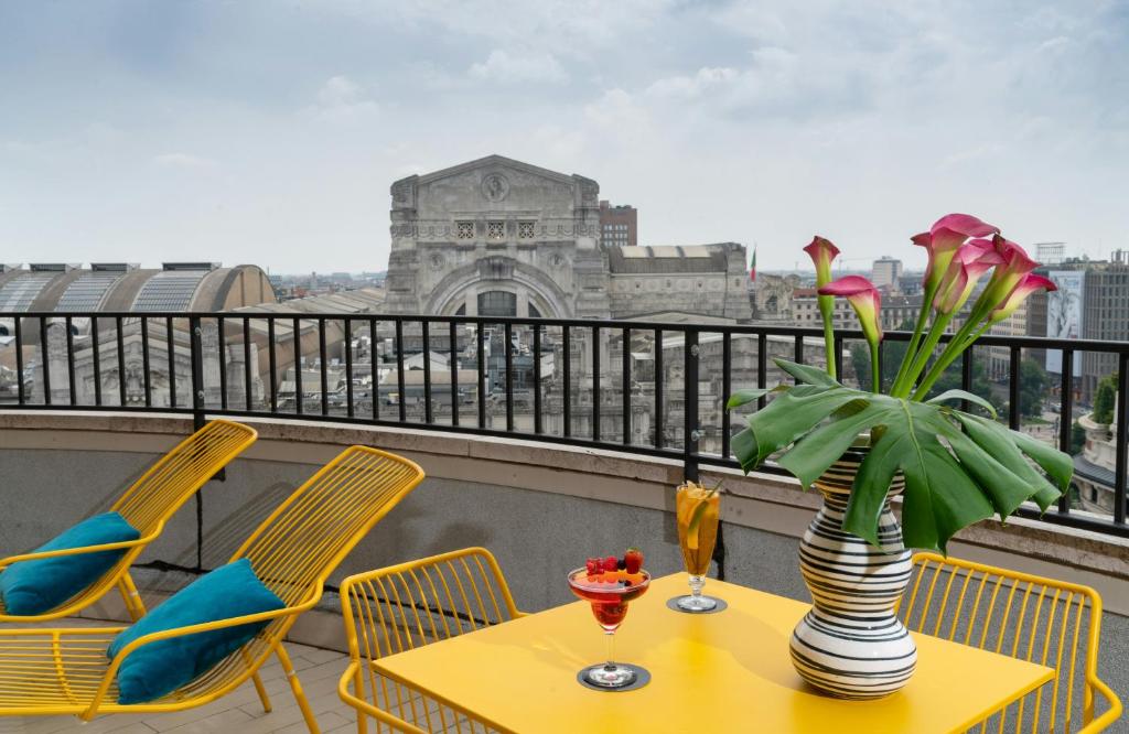 a table with a vase of flowers on a balcony at NYX Hotel Milan by Leonardo Hotels in Milan