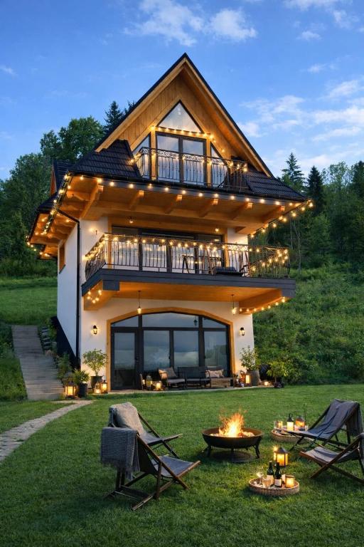 a house with a deck and a fire pit in the yard at Siedem Światów in Jurgów