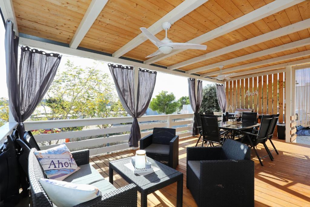 a porch with chairs and tables and a ceiling fan at Ahoi Hause 10 Strandhaus mit Meerblick & privatem Zugang in Drage