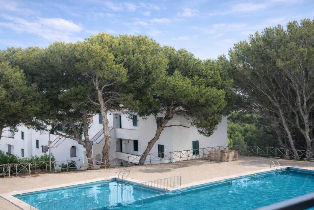 a villa with a swimming pool in front of a building at Sol Isla - Binimar in Arenal d'en Castell