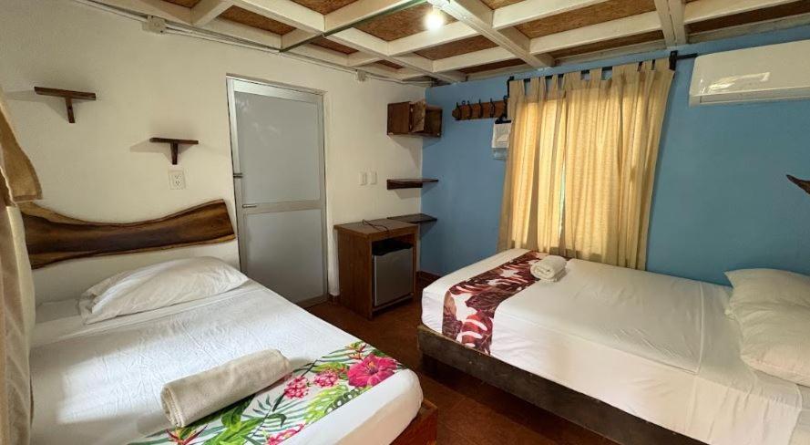 a bedroom with two beds and a blue wall at Hotel Frida Paradise in Brisas de Zicatela