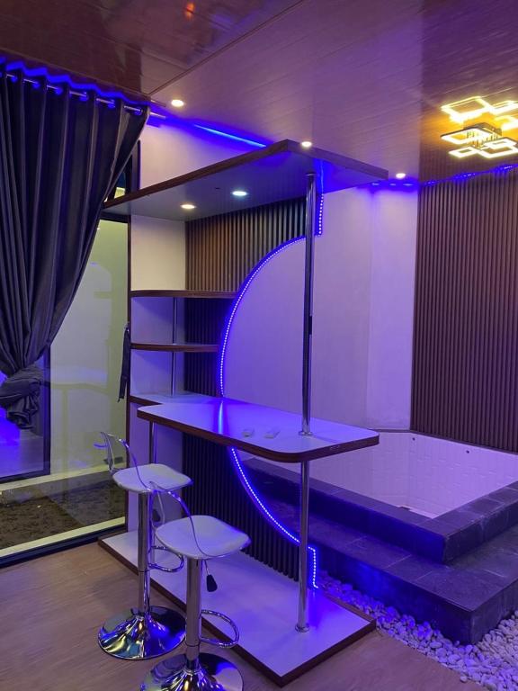 a table and two stools in a room with purple lights at HOUSEBOAT AFFA grup in Karanganyar